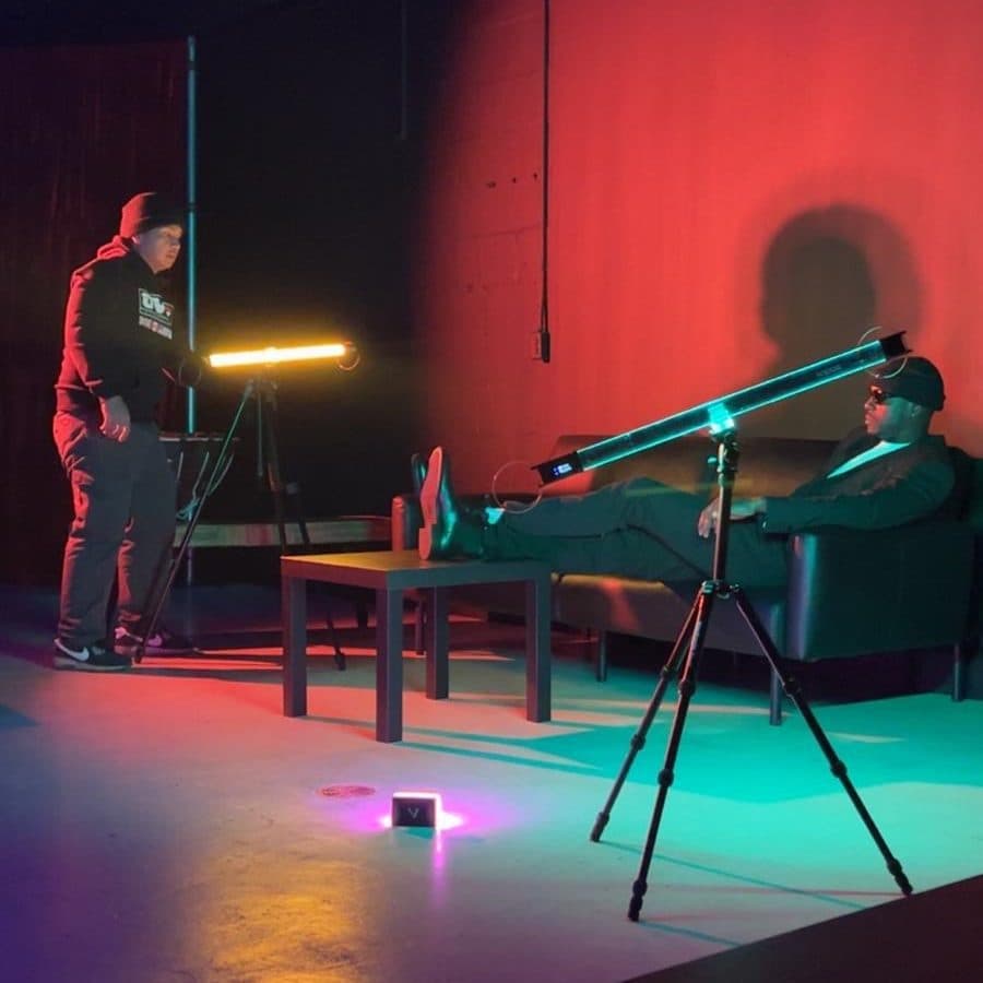 A video shoot at Half Note: a subject on a sofa lit by coloured LED tube lights on stands, against a red-lit wall.
