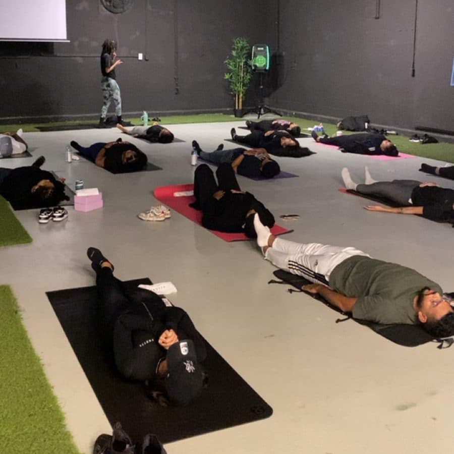 A yoga class at Half Note, with participants lying on mats across the open floor while the instructor stands at the front.